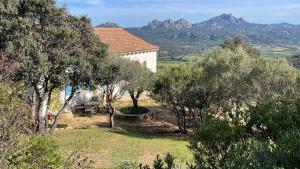 a house with trees and mountains in the background at Stazzu La Sarra in Cannigione