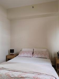 ein Schlafzimmer mit einem Bett mit einer weißen Tagesdecke in der Unterkunft Saint honore megaworld business park Iloilo City in Iloilo City