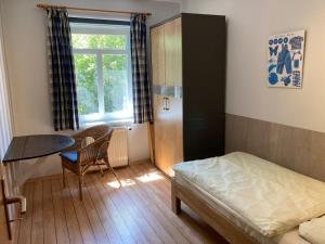 a bedroom with a bed and a table and a window at Dörpshus im strandnahen Bojendorf in Fehmarn