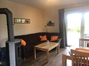 Una sala de estar con un sofá negro y una estufa de leña. en Dörpshus im strandnahen Bojendorf, en Fehmarn