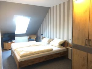 Un dormitorio con una cama con sábanas blancas y una ventana. en Dörpshus im strandnahen Bojendorf, en Fehmarn