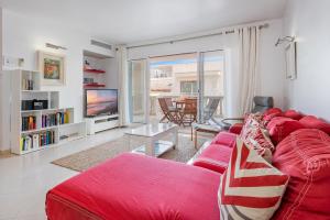 ein Wohnzimmer mit einem roten Sofa und einem Fernseher in der Unterkunft Sea Two in Port de Pollença
