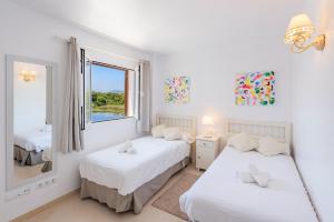 zwei Betten in einem weißen Zimmer mit Fenster in der Unterkunft Sea Two in Port de Pollença