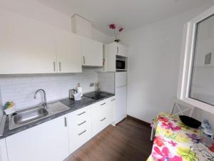 a kitchen with white cabinets and a sink and a window at CHC-Casa Cira in Los Silos