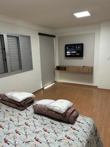 a room with two beds and a tv on the wall at Apartamento Praça Inconfidência Bom Despacho in Bom Despacho +14 photos