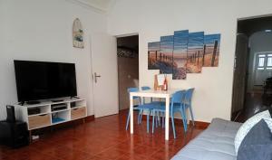 a living room with a table and chairs and a tv at Casa Ibaía, típica e acolhedora no centro de Olhão in Olhão