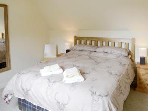 ein Schlafzimmer mit einem Bett mit zwei Handtüchern darauf in der Unterkunft Rowan Cottage in Glenrossal