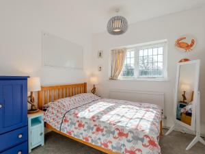 a bedroom with a bed and a blue cabinet and a window at The Barn in Hunstanton