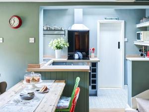 eine Küche mit einem Holztisch mit Stühlen und einer Theke in der Unterkunft Rose Cottage in North Elmham