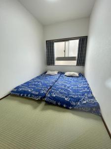 a bedroom with a bed with a blue comforter and a window at NEW Open Otsuka Sakura - Nearby Sunshine Ikebukuro in Wada