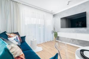 a living room with a blue couch and a tv at Apartament AQUAMARIN Sarbinove Prestige by BALTIC CLUB in Sarbinowo