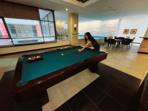 a woman playing pool in a room with a pool table at Ecuabook Torre Sol Family Apartment 901 in Guayaquil