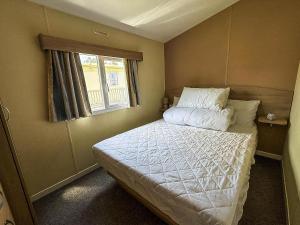 een kleine slaapkamer met een bed met witte lakens en een raam bij Lovely 8 Berth Caravan At Southview Holiday Park, Skegness Ref 33023M in Skegness +17 foto's
