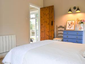 a bedroom with a white bed and a blue dresser at Pigaway Cottage in Petrockstow