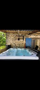 a hot tub in a room with a stone wall at Mas de Chalvagne in Val-de-Chalvagne