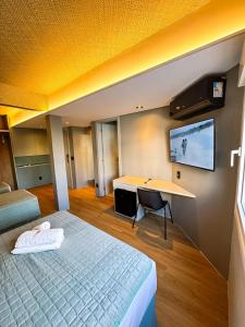 um quarto com uma cama, uma escrivaninha e uma TV em Hotel Zata - Premium em Criciúma