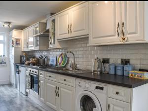 a kitchen with white cabinets and black counter tops at La Casita in Herne Bay