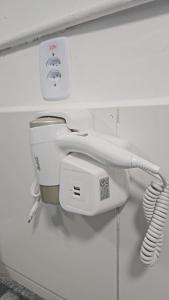 a bathroom with a toilet and a phone on a wall at Nobre Flats 201 in Petrolina