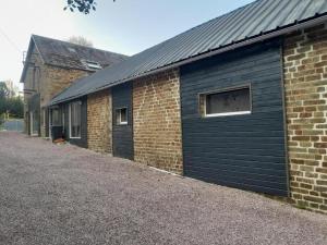 een gebouw met blauwe garagedeuren naast een bakstenen gebouw bij king conde in Saint-Pierre-du-Regard