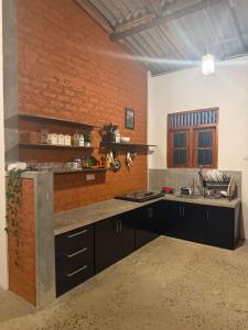 a kitchen with black cabinets and a brick wall at Mahiyanganaya Holiday Resort in Mahiyangana