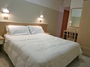 Hotel Romina في ريميني: سرير أبيض كبير في غرفة نوم بها مصباحين