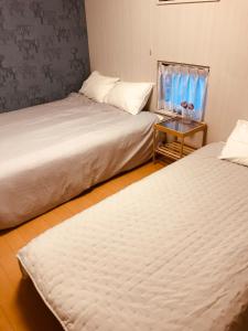 松山民泊 月的小型客房配有两张床和一张桌子。 更多36张照片