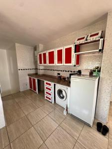 a small kitchen with red cabinets and a white refrigerator at Duplex à Rincón Vue mer in M'diq