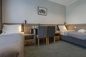 a hotel room with two beds and a desk with a chair at Willa Zdrojowa PARK Sauna Jacuzzi Fitness Dostęp do zabiegów Leczniczych Rehabilitacyjnych & Restauracji in Busko-Zdrój