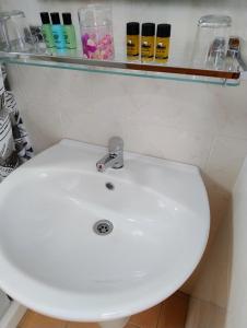 ein weißes Waschbecken in einem Badezimmer mit einem Regal darüber in der Unterkunft Mpezas Studios in Igoumenitsa