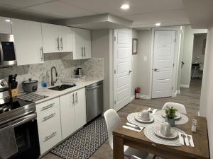 a kitchen with white cabinets and a table and chairs at The Place in Winnipeg