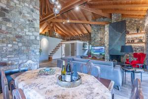 a dining room with a table and chairs and a stone wall at PIETRA VILLA Akoli beach in Rodhodháfni