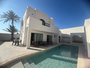 a house with a swimming pool in front of it at Villa Eden Djerba in Djerba