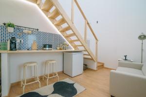 a living room with a staircase and a kitchen with stools at Loft 11 in Olhão