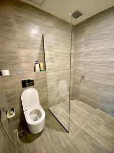 a bathroom with a toilet and a glass shower at Opus Luxury Family Serviced Apartments Gulberg Lahore in Lahore