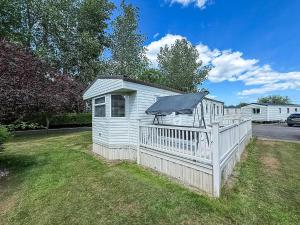 a small white shed with a fence and an umbrella at Great Caravan With Spacious Decking Southview Holiday Park, Skegness Ref 33035V in Skegness