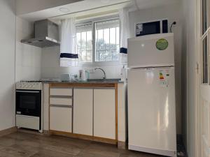 a kitchen with white appliances and a white refrigerator at Casa Vélez - cómoda, moderna y bien ubicada en Tres Arroyos in Tres Arroyos +29 photos