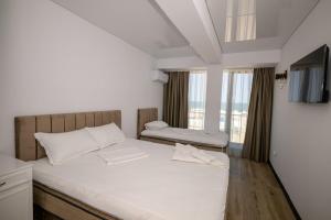 a bedroom with a bed with white sheets and a window at Miraky Beach in Văleni