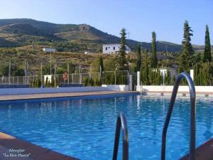a swimming pool with blue water and a hill at Casa Estrella de la Alpujarra in Almegíjar