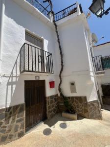 a white building with a gate and a balcony at Casa Estrella de la Alpujarra in Almegíjar