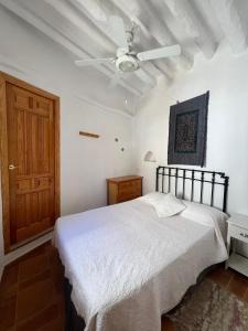 a bedroom with a white bed and a ceiling fan at Casa Estrella de la Alpujarra in Almegíjar +52 photos
