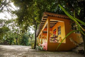 Un pequeño edificio naranja con una ventana y árboles. en Lakou Breda, en Cabo Haitiano