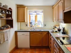 a kitchen with wooden cabinets and a sink and a window at Carters Cottage in Puncknowle