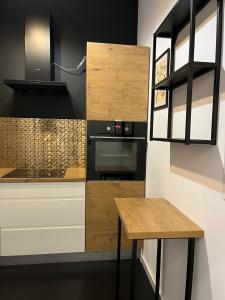 cocina con armarios de madera, mesa y fogones en Apartament P52 Wrocław, en Wroclaw