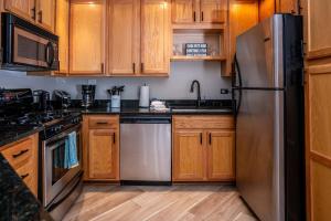 a kitchen with wooden cabinets and a stainless steel refrigerator at Stay in Abbey Springs 2 BDR with Resort Amenities in Lake Geneva +22 photos