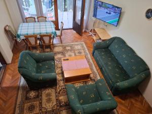 a living room with a green couch and chairs at Szőlő Vendégház Balatongyörök in Balatongyörök
