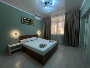 Un dormitorio con una cama grande y una ventana. en Green Hotel, en Tashkent