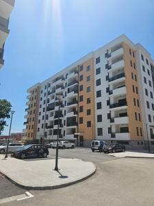 ein großes Apartmenthaus mit Autos auf einem Parkplatz in der Unterkunft Dvosoban stan Akacija Trebinje in Trebinje