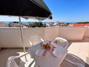 a white table with a bowl of fruit and an umbrella at Apartmani Dorana in Vrsi