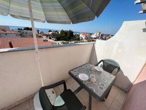 a table and chairs on a balcony with an umbrella at Apartmani Dorana in Vrsi