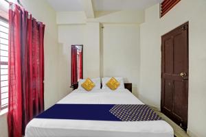 a bedroom with a large bed with red curtains at Hotel O Vishu Moni Residency in Mysore